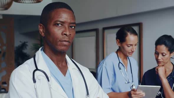 Front view of African american doctor with arm crossed looking at camera at lobby in hospital 4k alt
