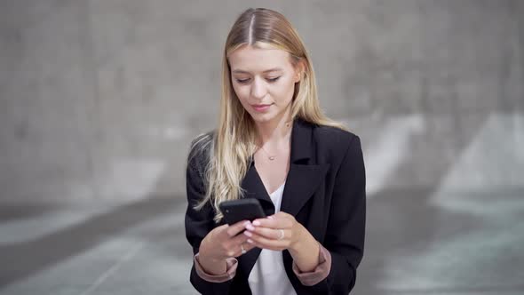 Blond Businesswoman Browsing Cellphone During Break alt
