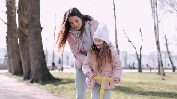 The Mother and Cute Daughter Are Walking in the Park alt
