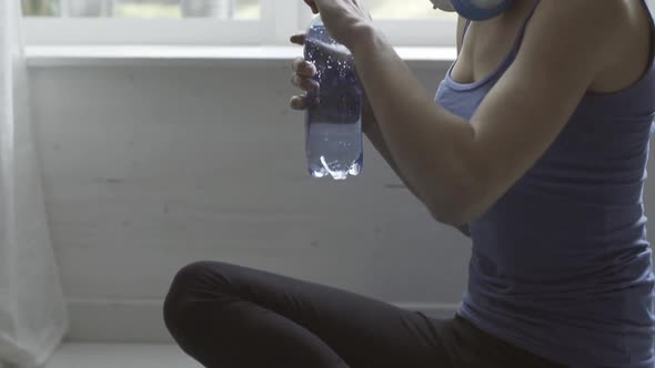 Woman drinking water after exercising at home
