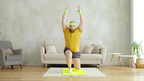 Fat Man Doing Squats in Lunges Exercise with Hands Up Standing on Mat at Home