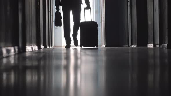 Businessman Walking with Luggage along Hallway in Hotel