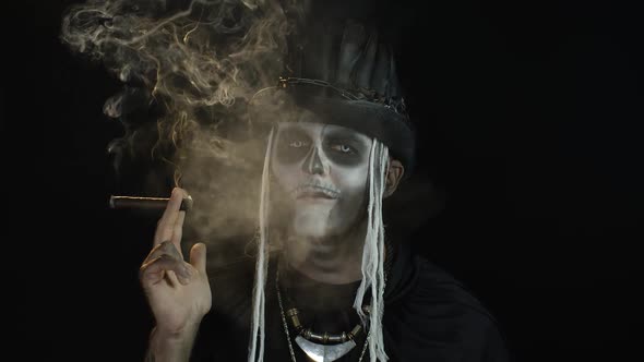 Sinister Man with Horrible Halloween Holiday Skeleton Makeup Raising His Head and Smoking Cigar alt