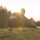 Young Woman Doing Stretching on a Sunset Background