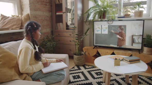 Afro-American Girl Watching Online School Lesson and Studying at Home alt