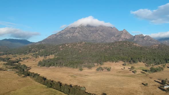 A high view of the rugged Mount Barney Australia  with the summit peak covered in a thick white clou alt