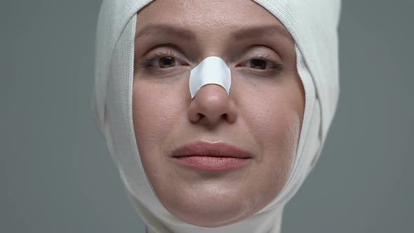 Woman in Elastic Bandage on Face Opening Eyes, Enjoying Plastic Surgery Result