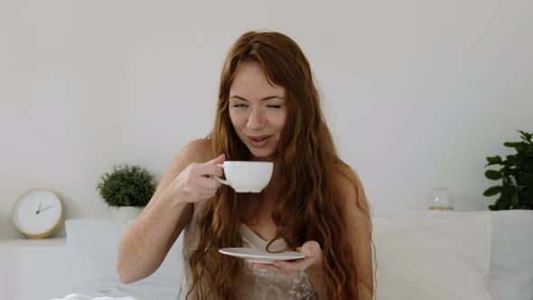 Portrait of beautiful happy woman drinking hot coffee,  in white bed in morning