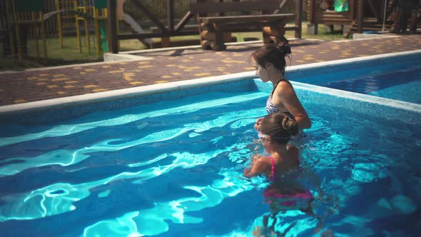 Elder Sister in Leopard Swimsuit Pulls Little Sister Out of the Pool with Blue Water alt