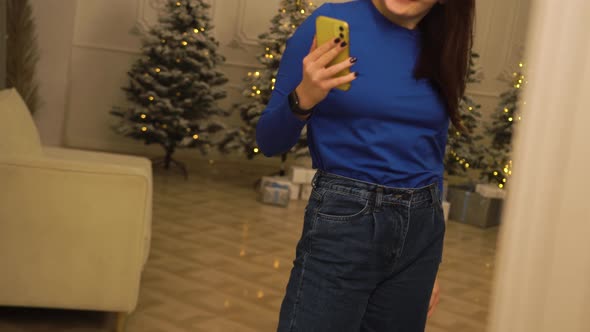 Woman is Photographed Near Large Mirror Against the Background of Christmas Tree