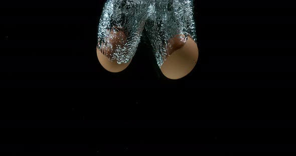 Chicken's Eggs entering Water against Black Background, Slow Motion 4K alt