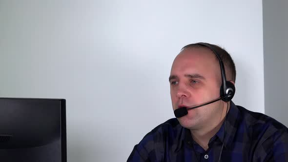 Confident Male Customer Service Representative with Headset in Front of Computer