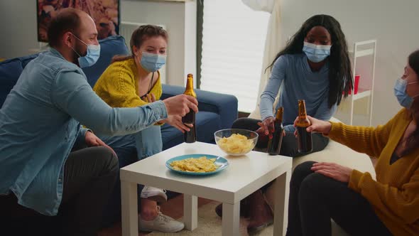 Happy Diverse People Having Fun in Living Room Clinking Bottles of Beer alt