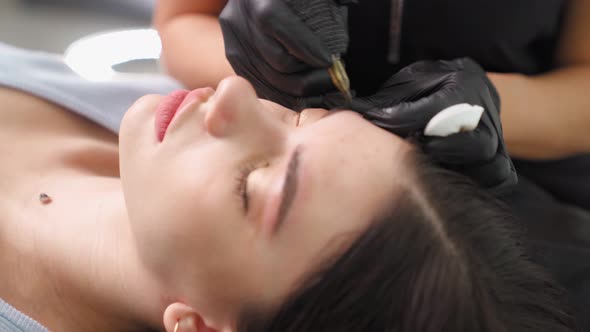 Master Makes Permanent Eyebrow Makeup Procedure to Woman in Beauty Salon alt