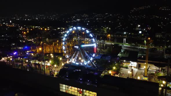 Night view of the city of Medellin, passing through an amusement park on the roof of a mall alt