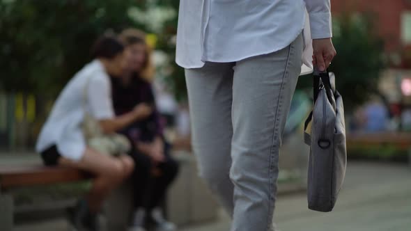 Business Woman Walking on the Way to Work Holding a Bag with a Laptop in Her Hand alt