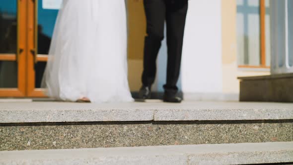 Woman in White Dress and Groom in Dark Suit Walk to Stairs alt