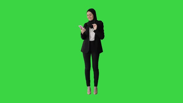 Muslim Girl in Hijab Using Smartphone To Send Voice Messages on a Green Screen Chroma Key alt