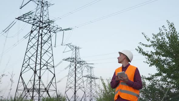 Engineer Inspects a Power Line Using Data From Electric Sensors on a Tablet.