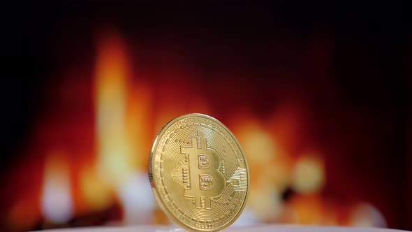 A Gold Bitcoin Coin Slowly Spinning Against the Background of a Burning Fire alt