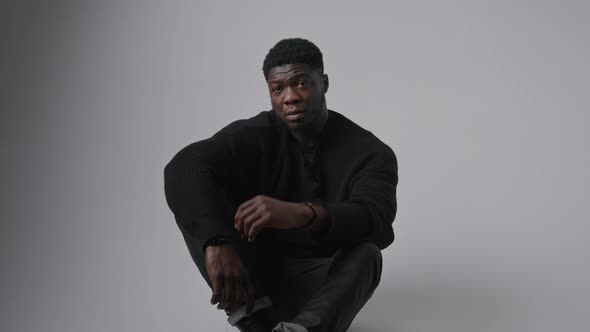 African American Man Sitting on the Floor Looking at the Camera Sad Emotions Closing Face with a alt
