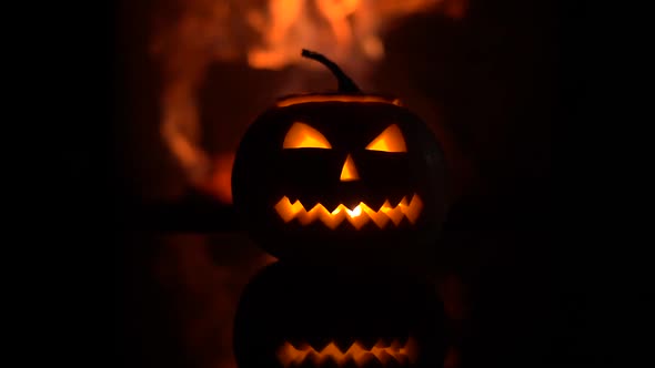 Creepy halloween pumpkin near a fireplace. Fire on the background.