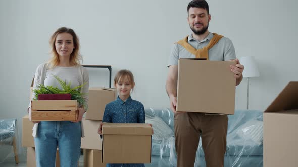 Portrait of Parents and Cute Child Holding Boxes Looking at Camera with Happy Faces During alt