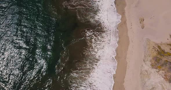 Aerial Top View Zoom Out Shot of Beautiful Foaming Ocean Waves Reaching Sunny Exotic Sandy Beach in alt