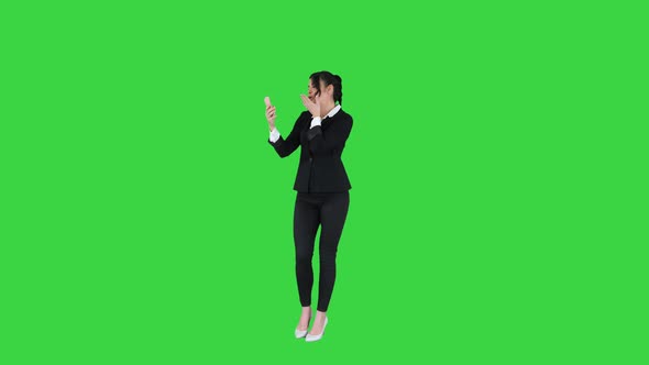 Business Woman Look Into Smart Phone Preening and Dancing on a Green Screen, Chroma Key. alt