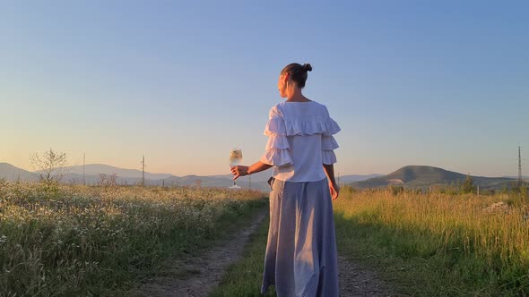 a woman with a glass walks through the field