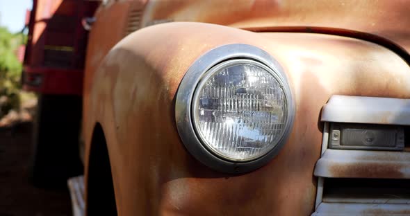 Slow slide left along the front of an old rusty vintage truck fender with glass headlight and grill alt
