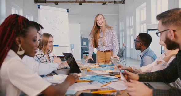 Healthy Workplace Atmosphere. Happy Positive Smiling Business Woman Talking To Multiethnic Employees alt