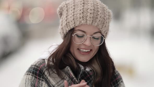 Portrait of a Beautiful Young Darkhaired Woman in Round Glasses and a Plaid Coat Walking on a Snowy alt