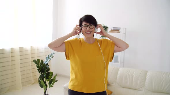 Beautiful Senior Woman Relaxed and Dancing, Listening To Music at Home. alt