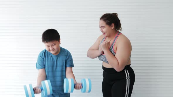 Fat mother cheers Fat son while lifting dumbbells for diet