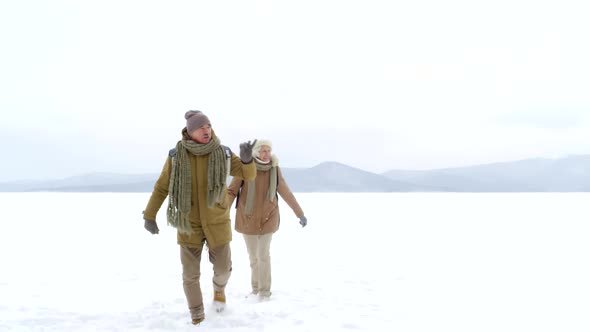 60-Something Caucasian Husband and Wife Walking in Snow and Chatting alt