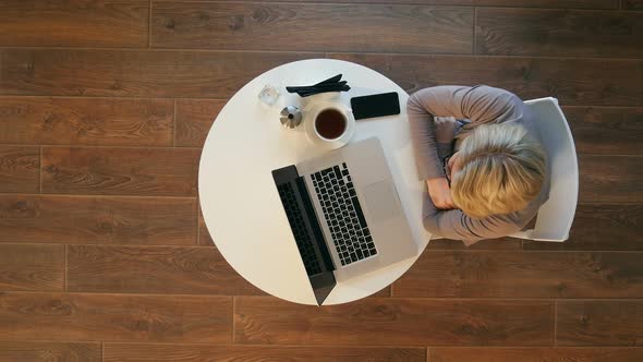 Beautiful Woman Putting on Glass and Working on Her Laptop on a Stylish Urban Restaurant alt