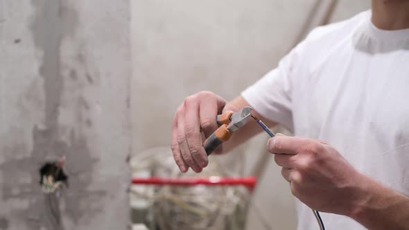 Electrician exposes wires, preparing them for connection with elements in the electrical network alt
