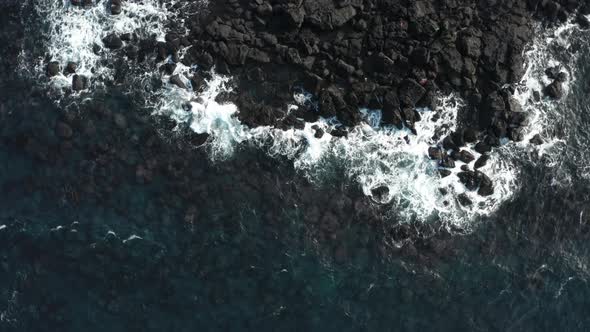 Wilderness landscape of transparent blue sea, waves and volcanic rocks.