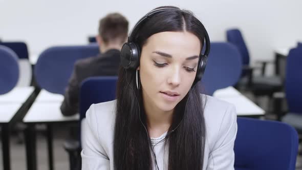Slim Beautiful Young Woman Listening to Music in Headphones Working in Office Indoors alt