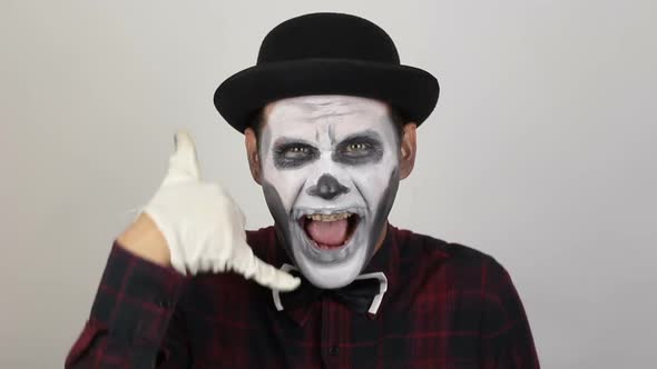 A Horrible Man in Clown Makeup Makes a Gesture Near His Ear Asking Him To Call Him Back. A Scary
