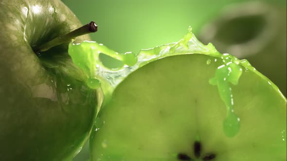 Slow Motion Shot of Green Apple Juice Splashing Through Apple Slices alt