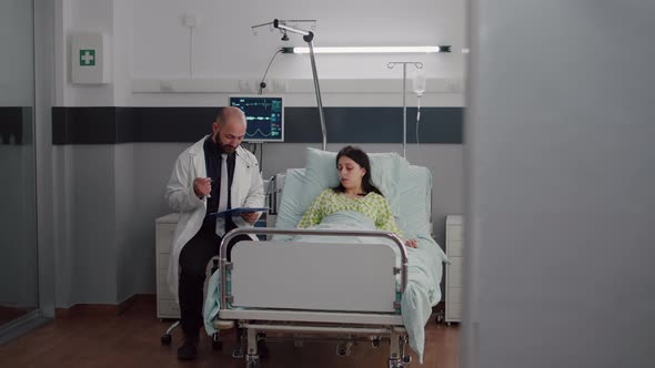 Front View of Sick Woman Resting in Bed Discussing with Oncologist Man Doctor alt