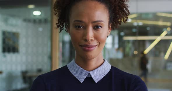 Portrait of smiling mixed race businesswoman in blue jumper standing in office alt