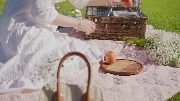 Woman Picking Fruits From Open Picnic Basket Placing on Wooden Plate at Summer alt