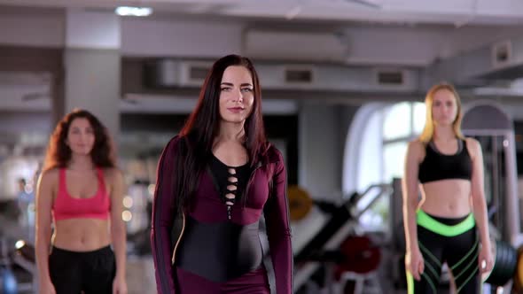 A Group of Beautiful Confident Female Athletes Cross Their Arms and Look at the Camera in the Gym