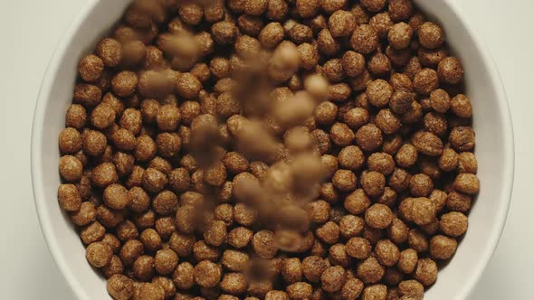 Chocolate Cereal Balls Falling Into A White Bowl