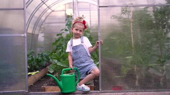a Little Girl Watering Vegetable Sprouts in a Greenhouse Gardening Caring for Plants in the Garden alt