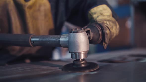 man polishes metal with special polishing machine alt