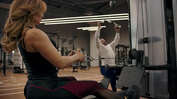 Couple in Good Physical Shape are Doing Exercises on a Exercise Machine alt
